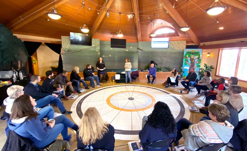 Four women stand in a half-moon circle discussing leadership.