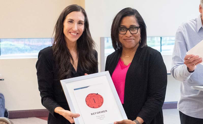 Four women stand in a half-moon circle discussing leadership.