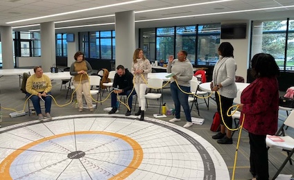 Four women stand in a half-moon circle discussing leadership.